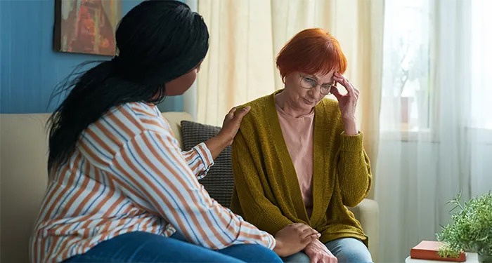 Woman comforts older friend feeling overwhelmed at home