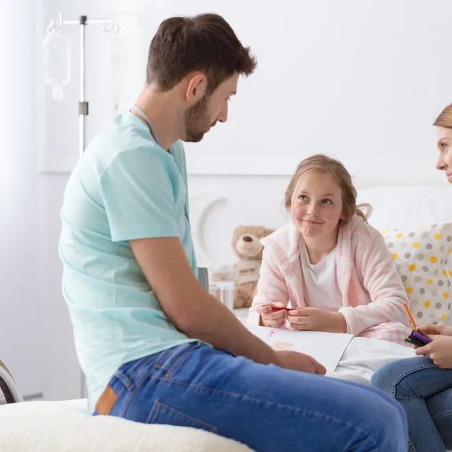 Child talking with two healthcare workers in a hospital room