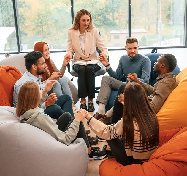 Therapist leads group counseling session in a bright lounge